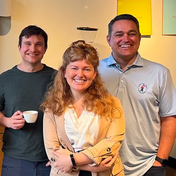 A group of three people posing for a photo in a café setting.
