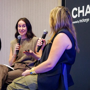 Two women engaged in a discussion with microphones in hand.