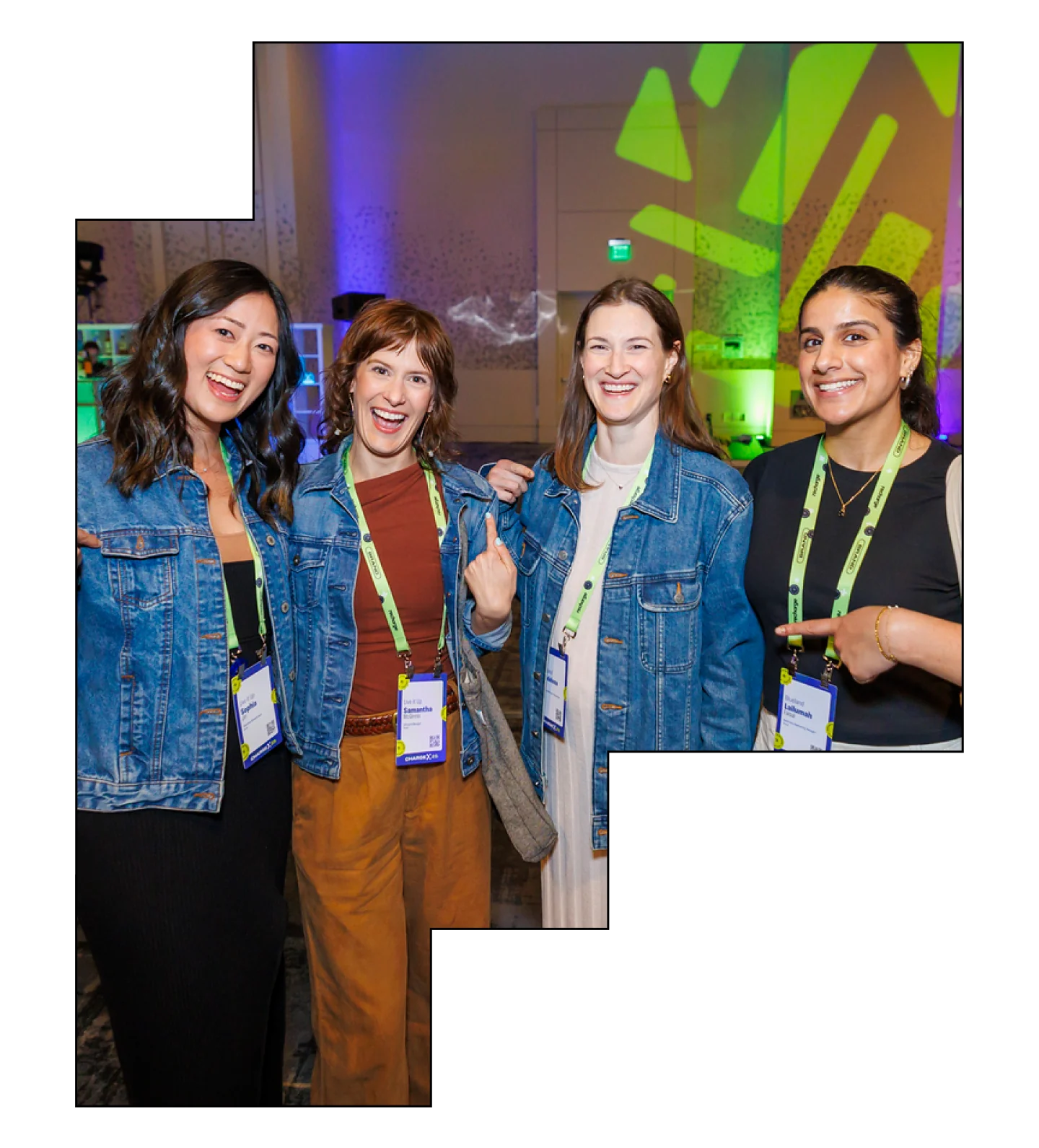 A group of four women posing and smiling in denim jackets at an event.