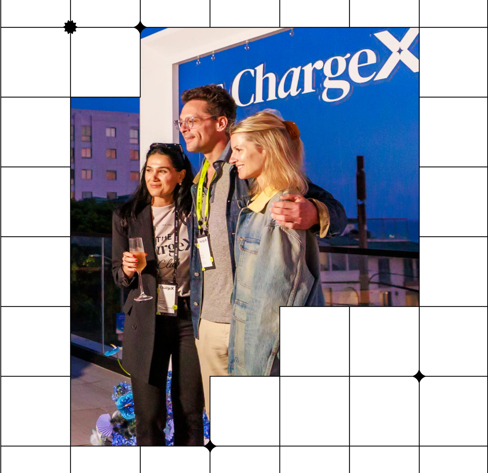 Three people posing together at an event with a ChargeX banner in the background.