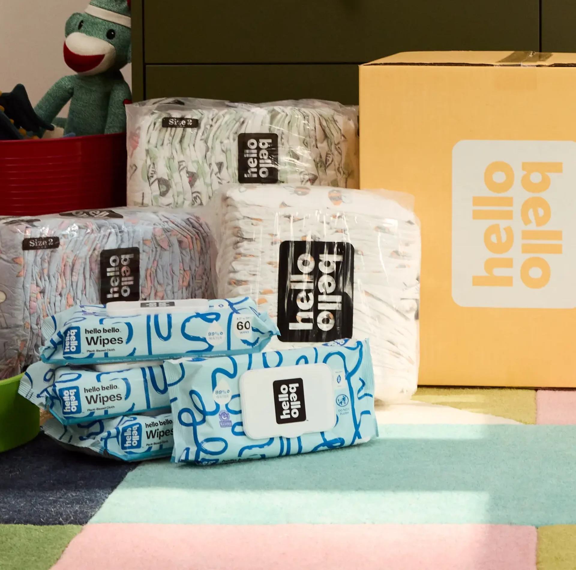 Packages of Hello Bello diapers and wipes stacked in a room.