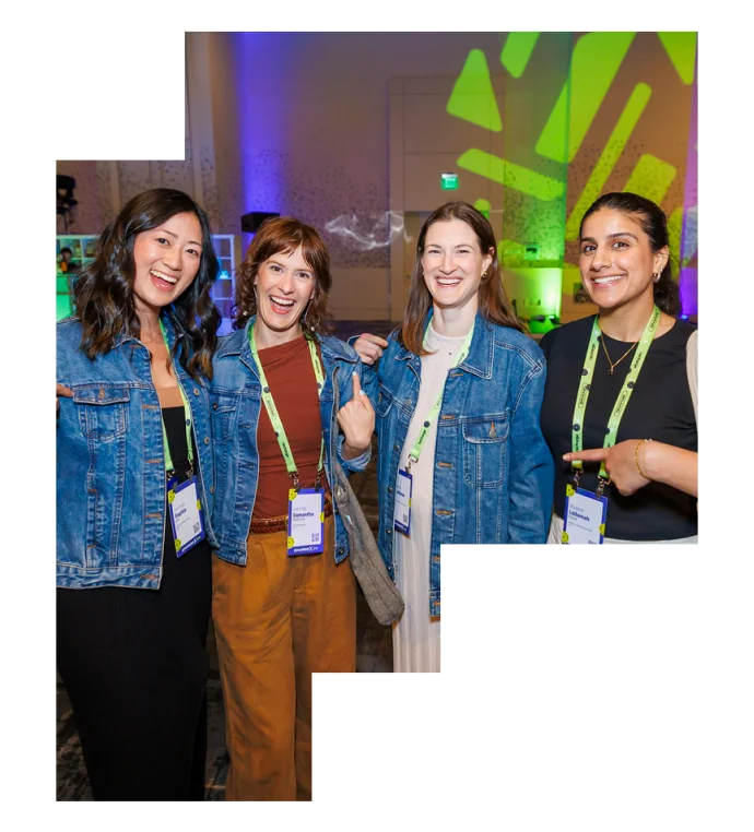Four individuals wearing denim jackets and lanyards smiling together at an event.