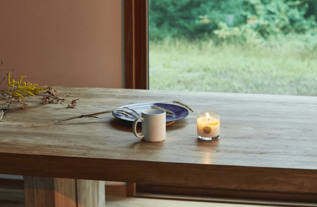 A Keap candle burns next to a mug of tea.