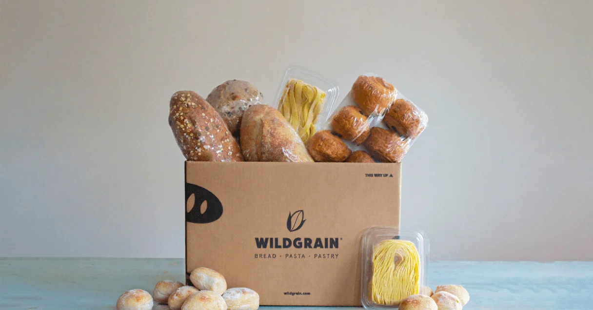 Cardboard box with the Wildgrain logo on the side and Wildgrain products coming out of the top