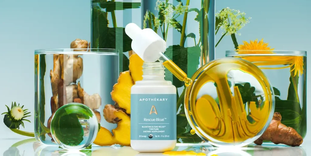 A bottle of Rescue Bloat tincture by Apothékary surrounded by various natural ingredients in glass containers.