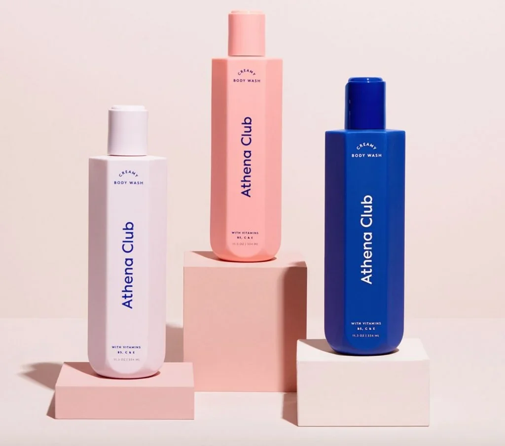 Assorted Athena Club body wash bottles arranged on pastel pedestals.