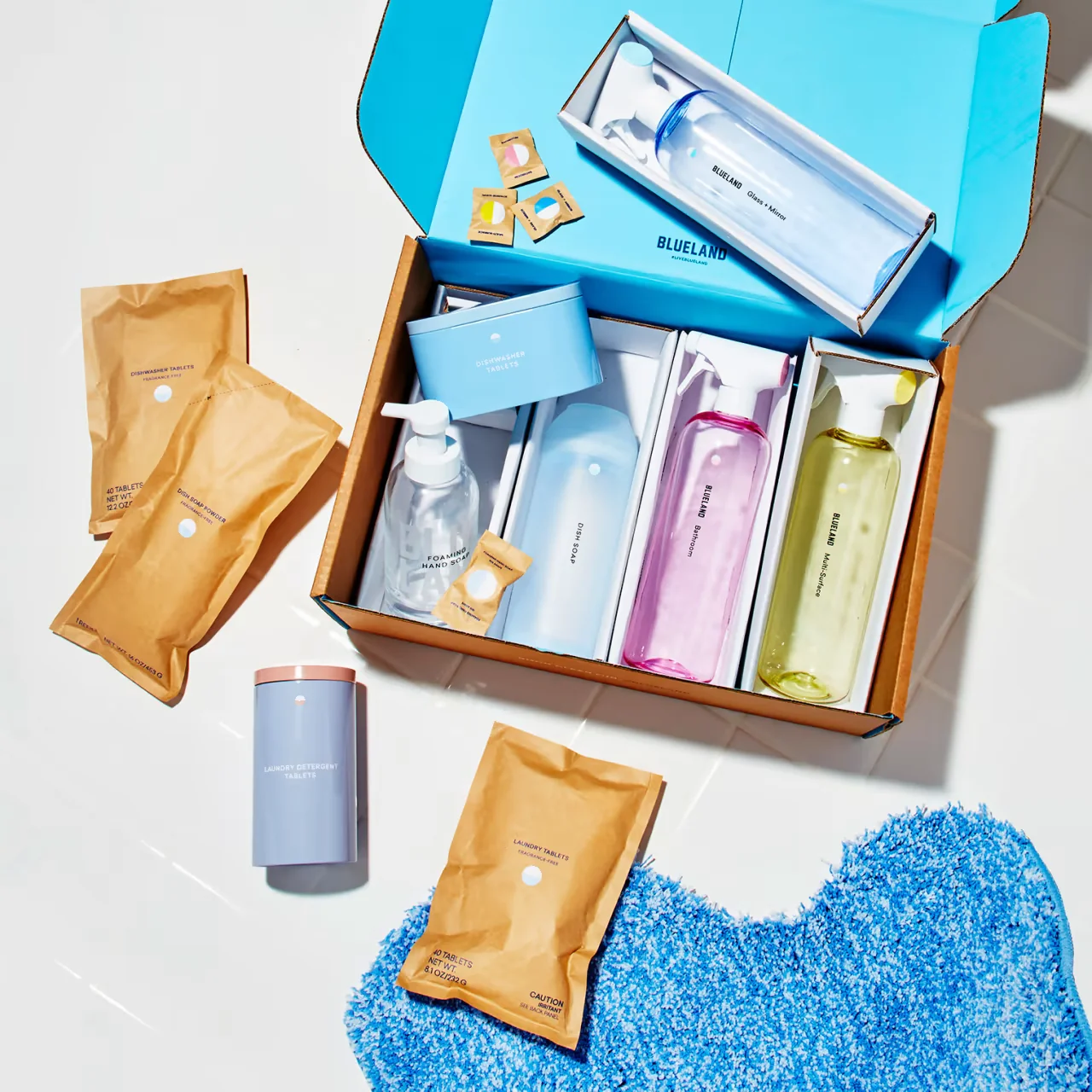 A variety of cleaning products, including bottles and tablets, displayed in a cardboard packaging.