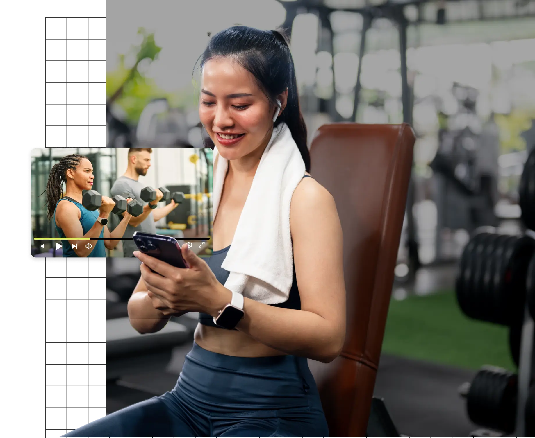 A person smiling, seated on a gym bench, watching a workout video on a smartphone.