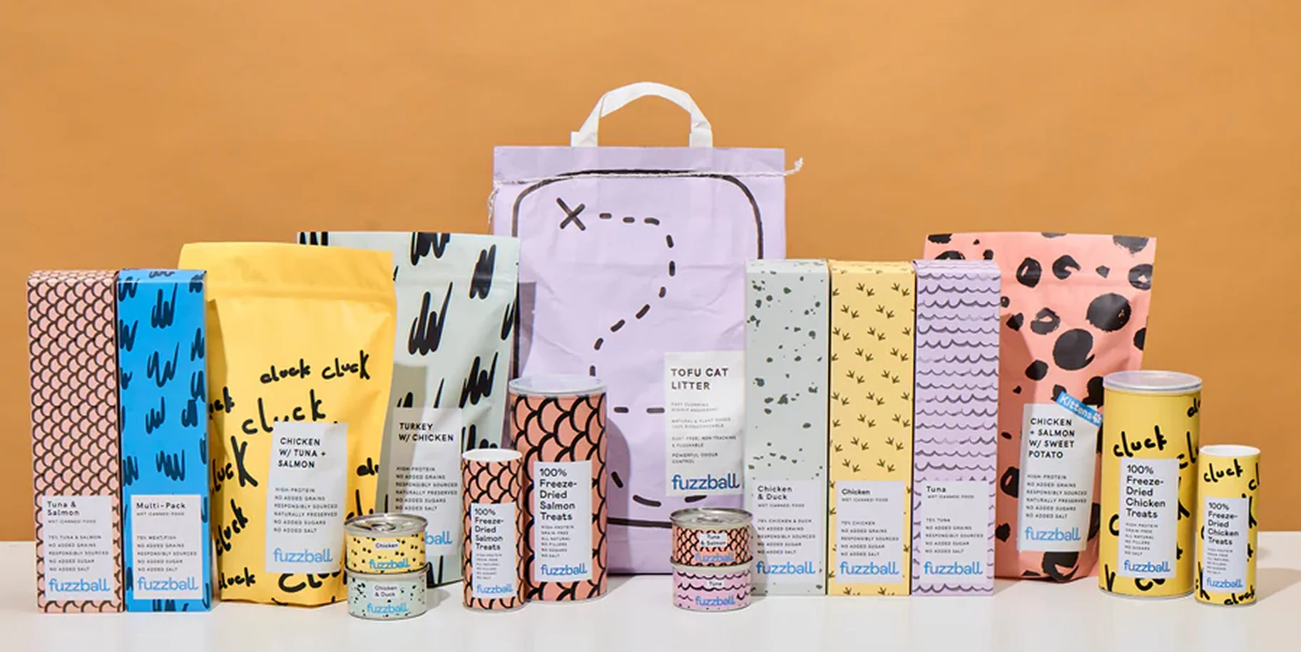 Various pet food products from Fuzzball displayed against a beige background.