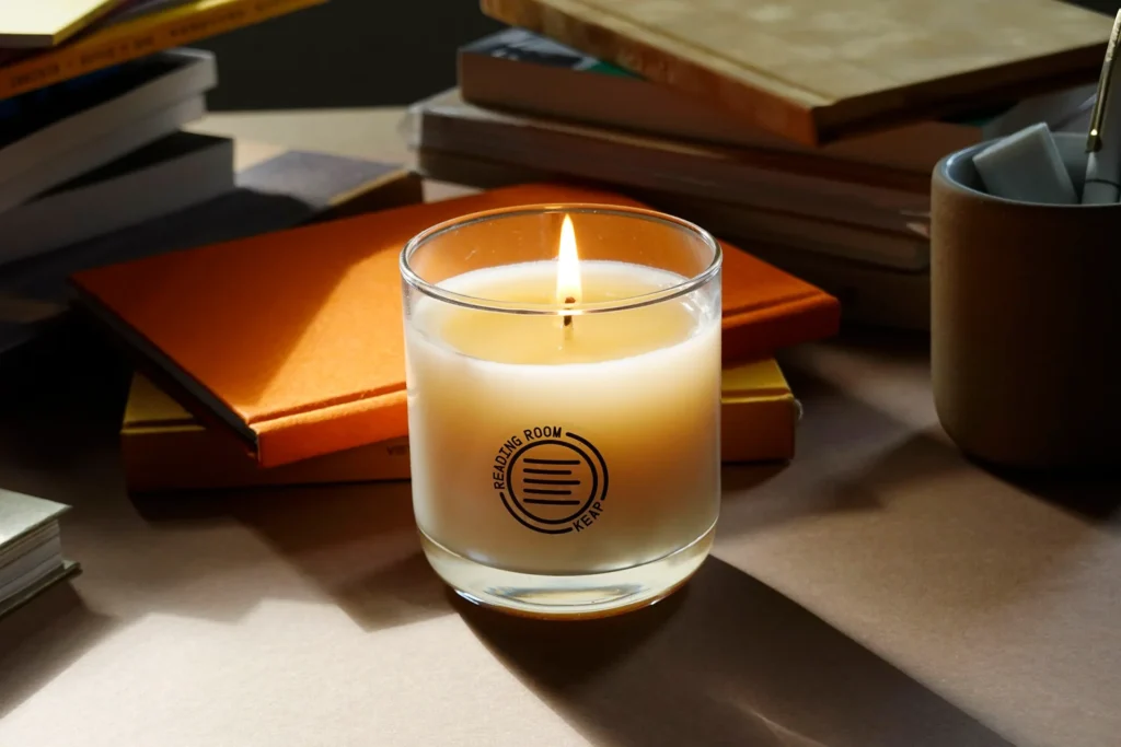 A lit candle on a table next to books and a small container.