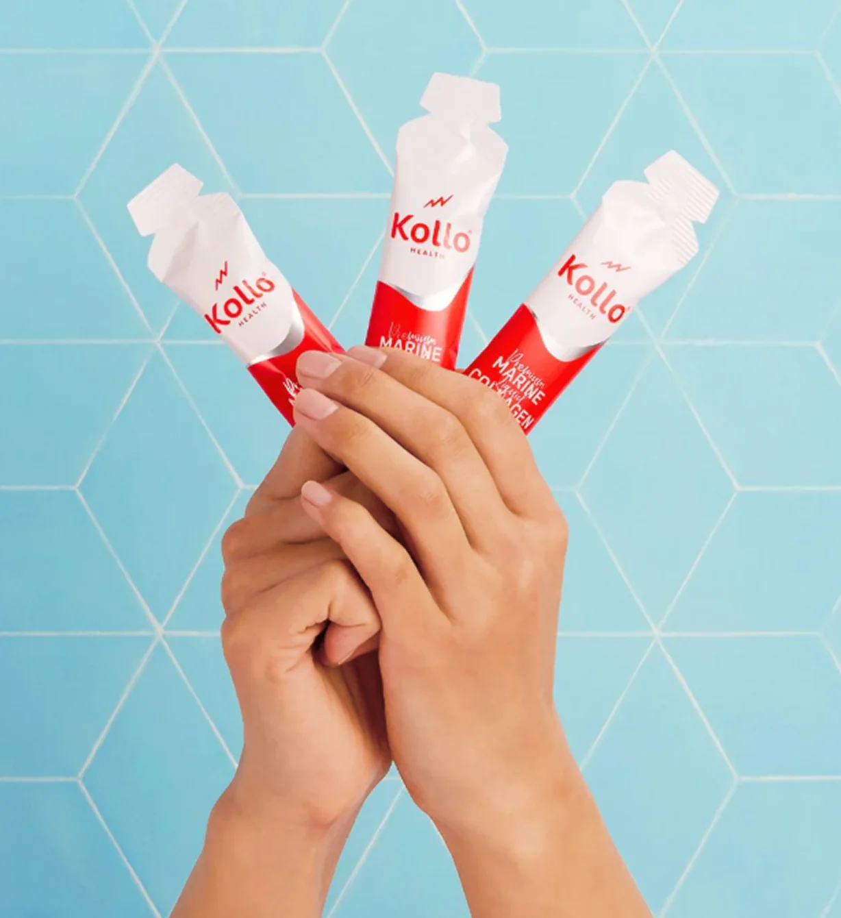 A person holding three pouches of Kollo Marine Collagen against a blue backdrop.