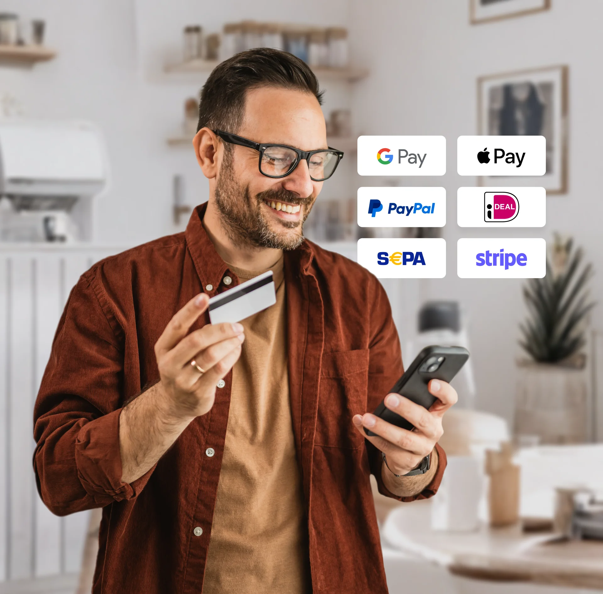 A person smiling while holding a credit card and checking their phone with various payment option logos displayed.