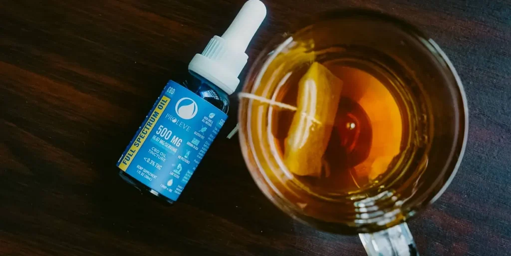 A Proleve full spectrum oil bottle next to a cup of tea.