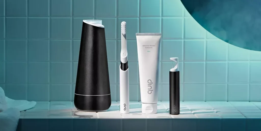 A lineup of dental care products including a toothbrush, toothpaste, and a water flosser on a tiled surface.