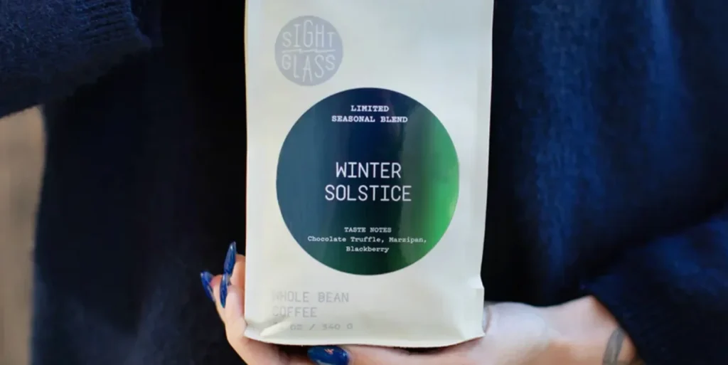 A person holding a coffee bag labeled Winter Solstice from Sight Glass.