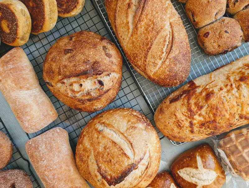 An assortment of various breads displayed on a cooling rack.