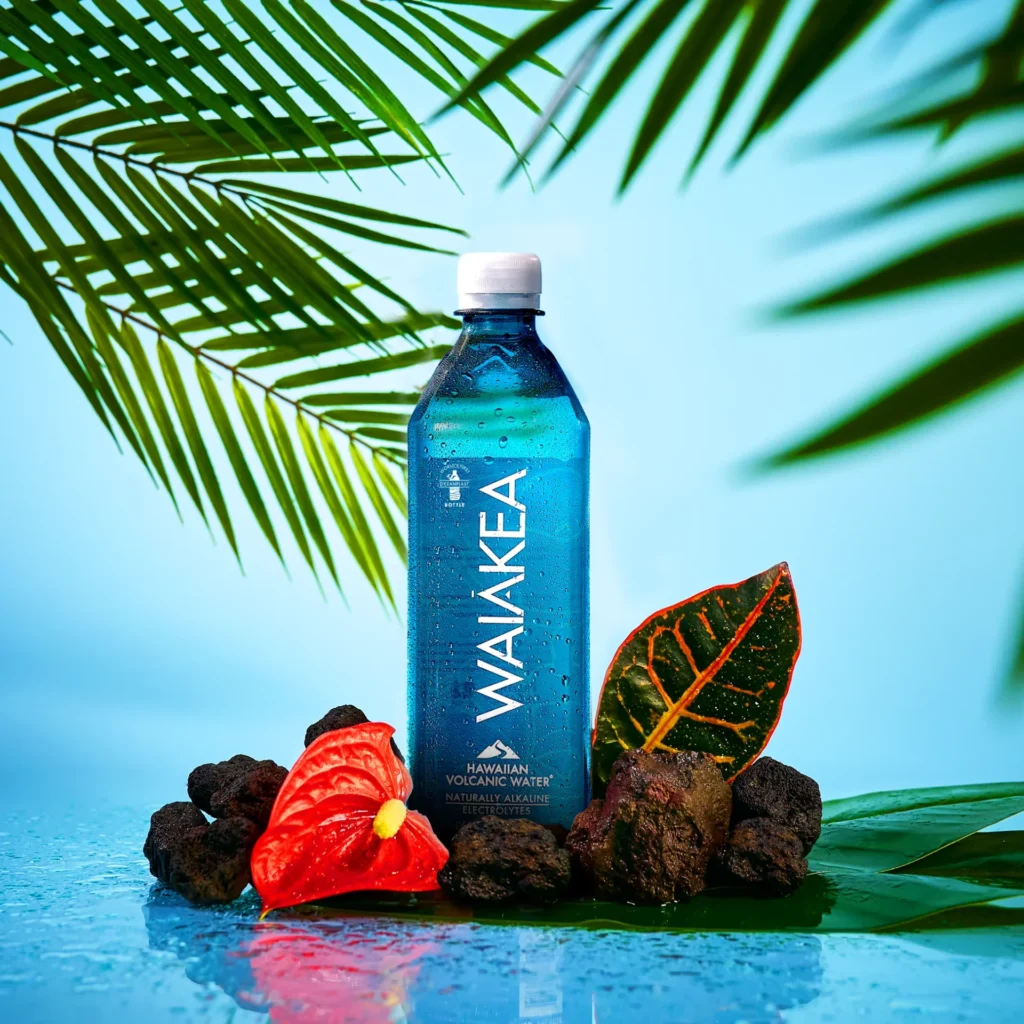 A Waiākea bottle surrounded by tropical leaves and volcanic stones.