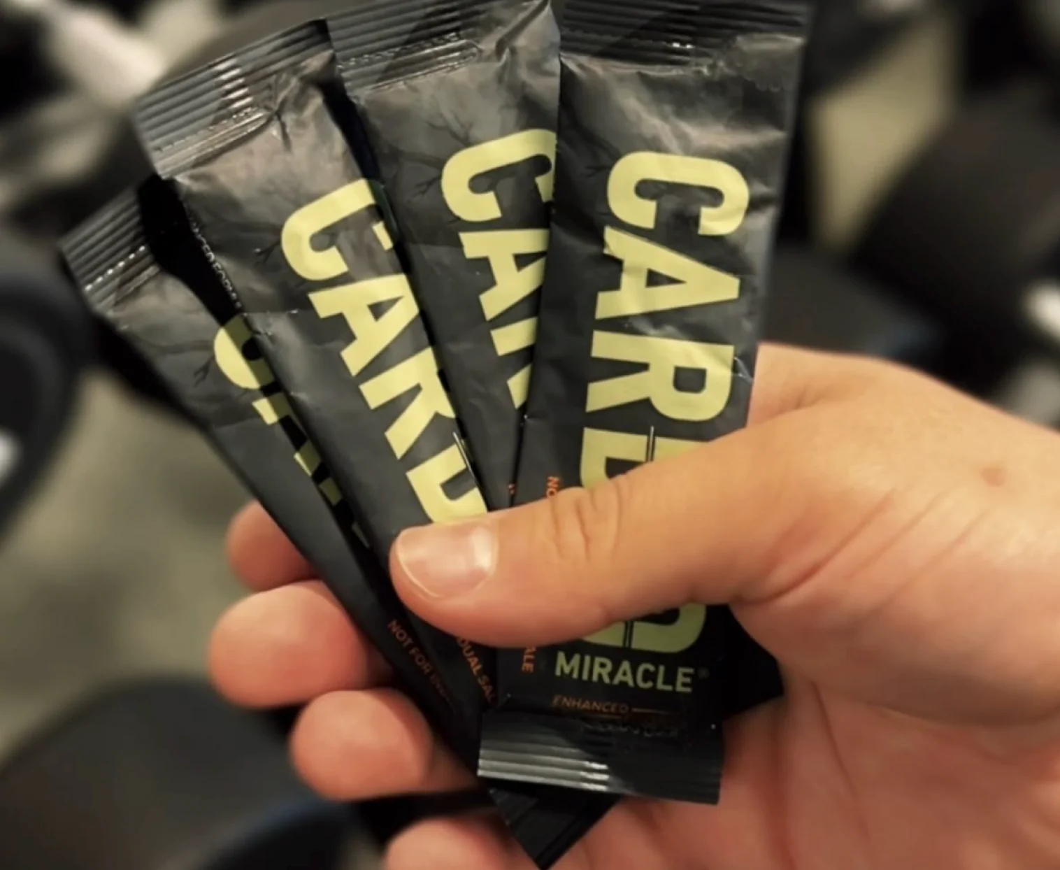 A hand holding multiple packets of Carb Miracle.
