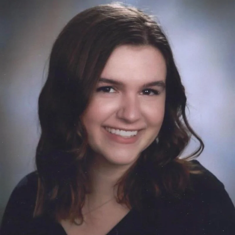 A person with shoulder-length wavy hair smiles at the camera.