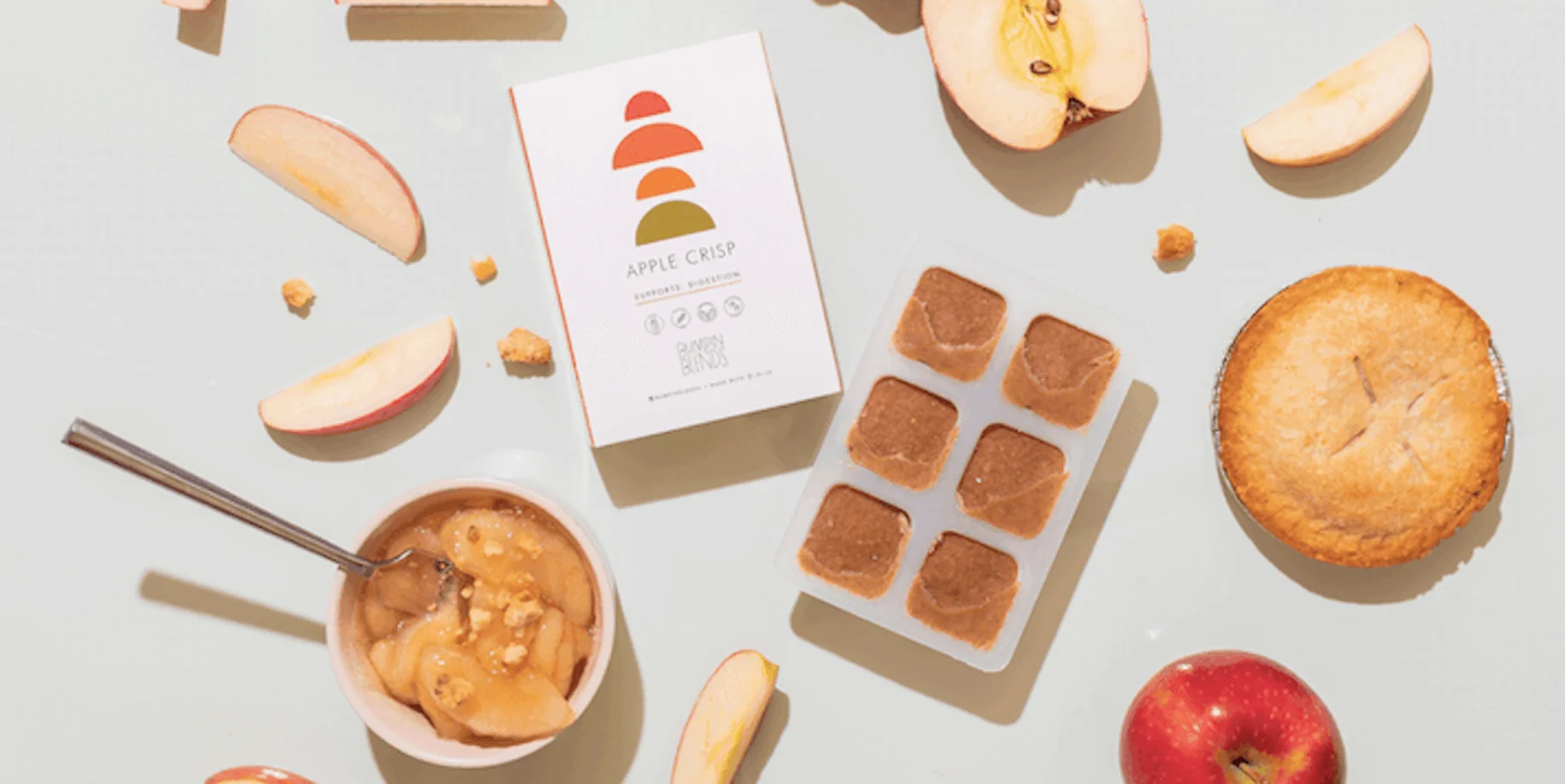 A bowl of apple crisp dessert with apple slices and a pie surrounded by apple-themed products.