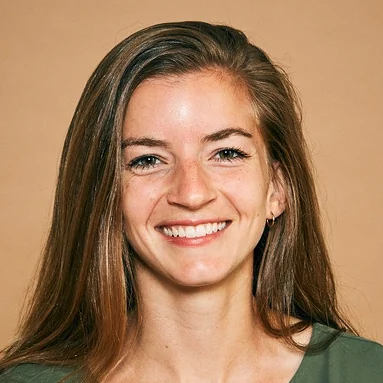 A smiling woman with long brown hair wearing a green top.
