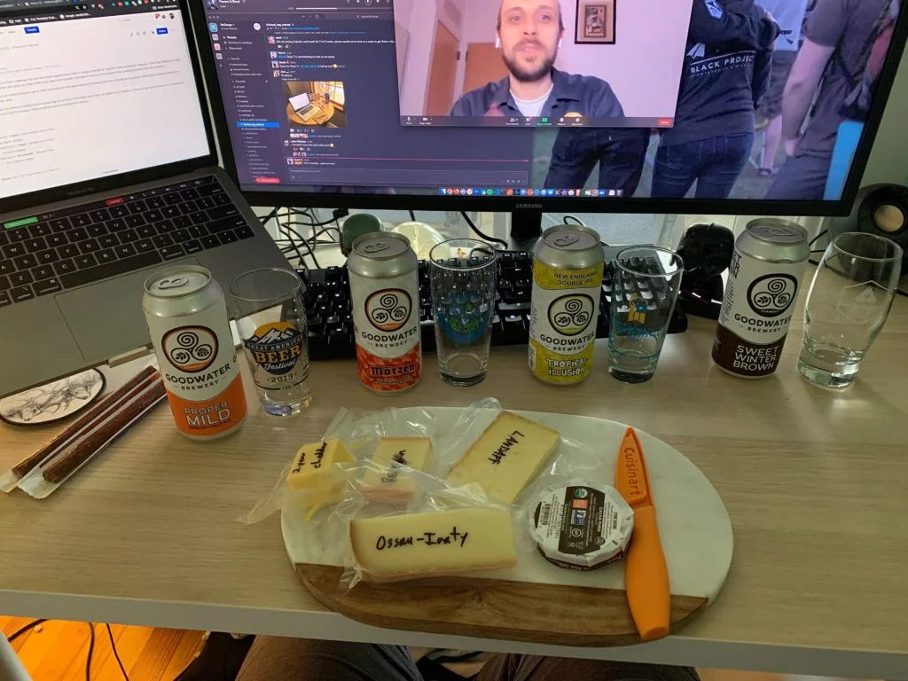 A home office setup featuring beer cans and cheese on a wooden board.