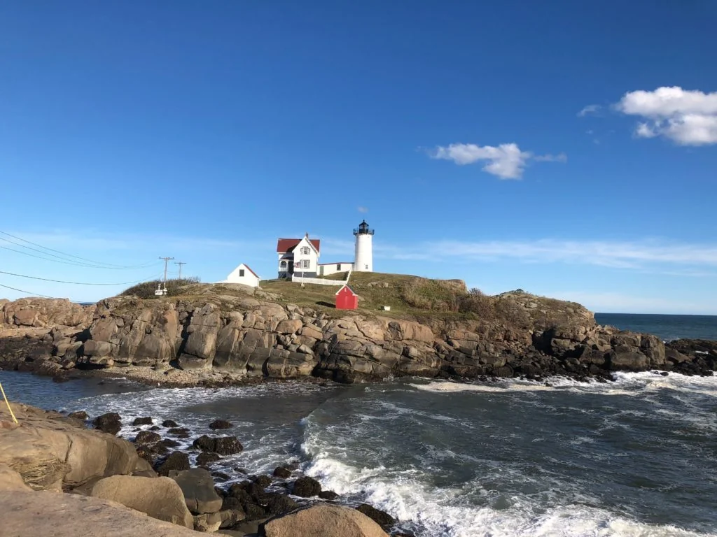 A lighthouse on a rocky shore with ocean waves.