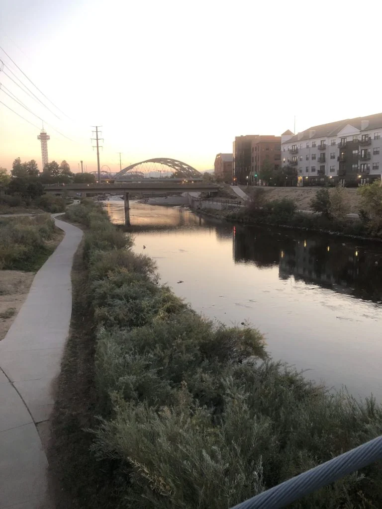 A river view during sunset with a bridge and buildings.