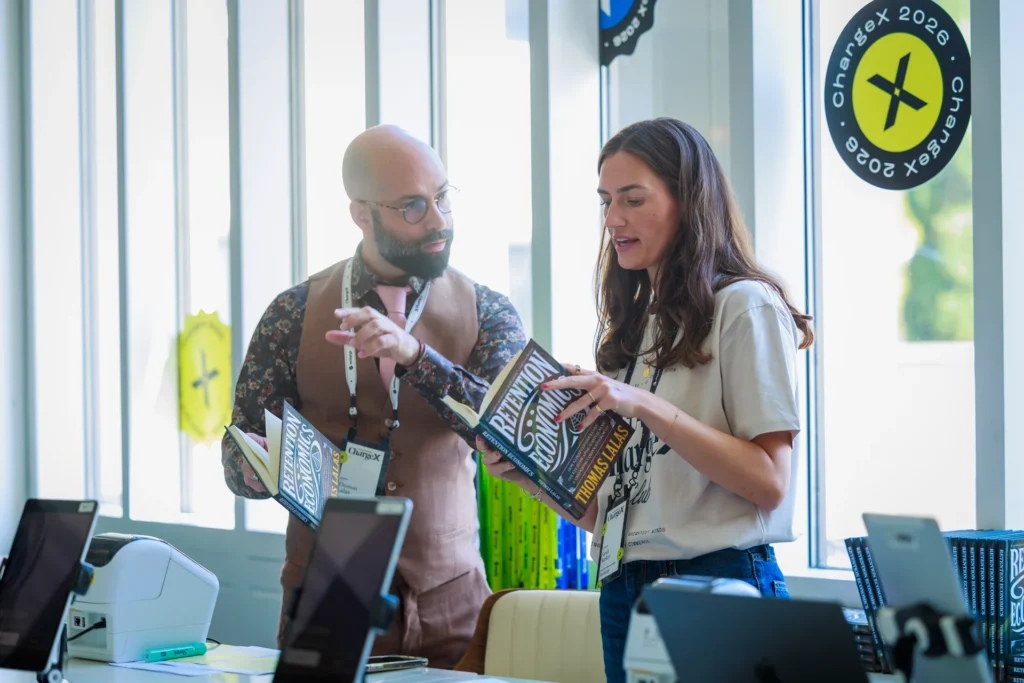 Two individuals engage in a discussion while holding books at the ChargeX event.