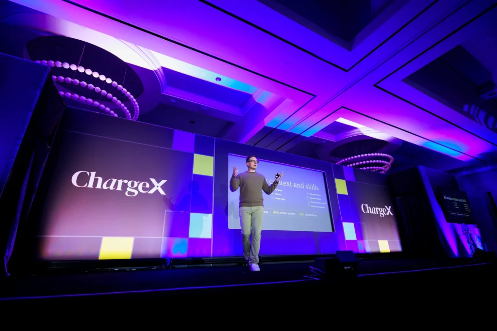 A speaker presenting on stage at the ChargeX event.