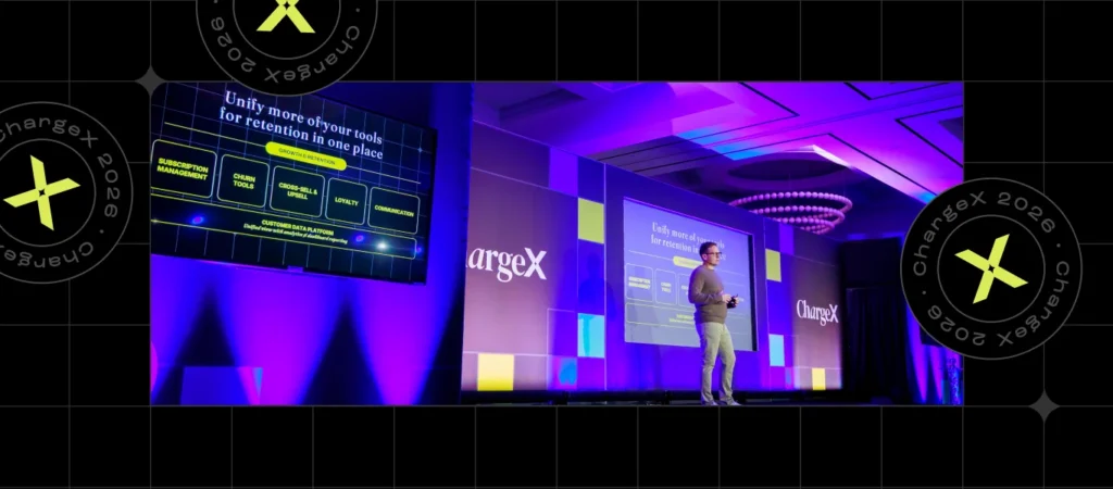 A person speaking at a presentation on stage with a large screen displaying retention tools.