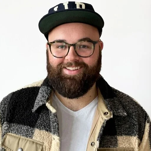 A person with a beard and glasses smiling at the camera.