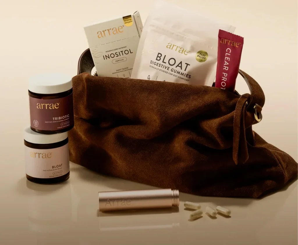 A brown suede bag containing various Arrae wellness products including Tribotic, Bloat, and Clear Protein.
