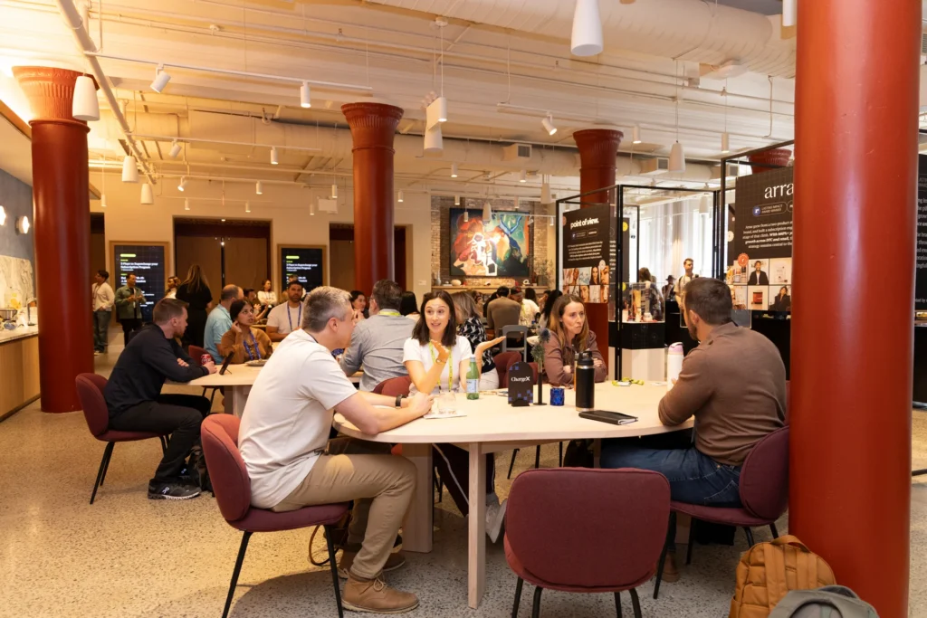 A group of people engaged in conversation around a table in a modern workspace.